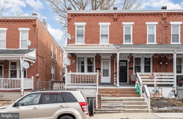 view of property with a porch and brick siding