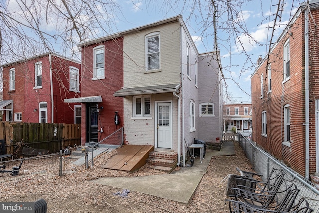 view of front of home with entry steps, brick siding, and a fenced backyard