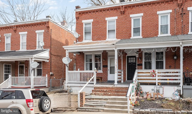 townhome / multi-family property featuring covered porch and brick siding