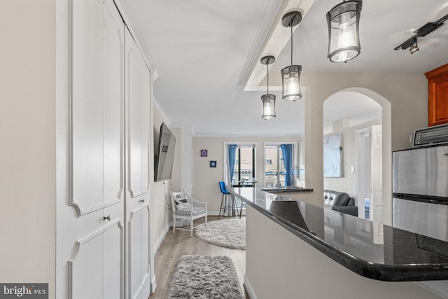 kitchen featuring stainless steel fridge, ornamental molding, light hardwood / wood-style floors, decorative light fixtures, and kitchen peninsula