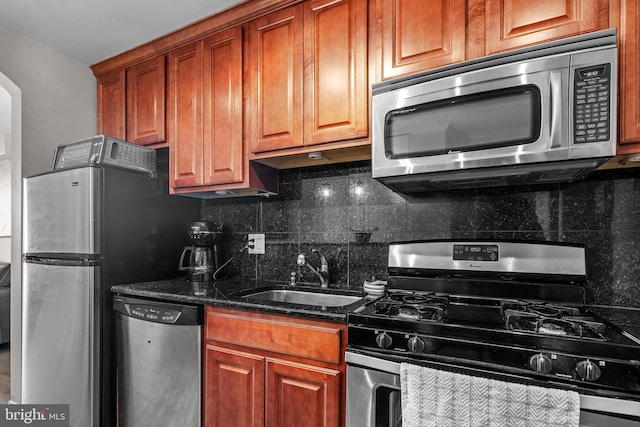 kitchen with dark stone countertops, sink, tasteful backsplash, and appliances with stainless steel finishes