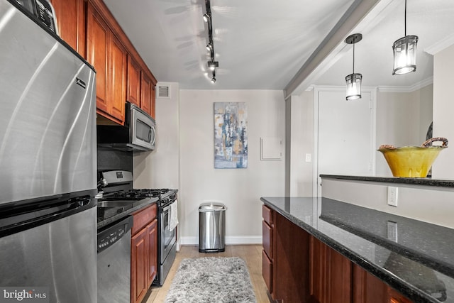 kitchen featuring appliances with stainless steel finishes, dark stone counters, hanging light fixtures, ornamental molding, and light wood-type flooring