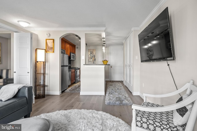 living room featuring wood-type flooring, a textured ceiling, and crown molding