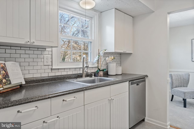 kitchen featuring dishwasher, sink, white cabinets, backsplash, and light tile patterned floors