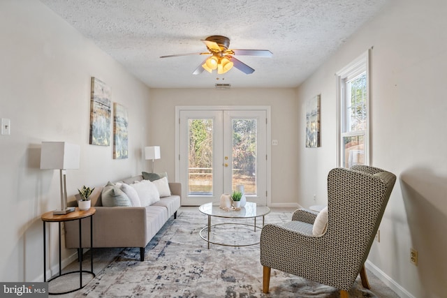 sitting room with ceiling fan, plenty of natural light, a textured ceiling, and french doors