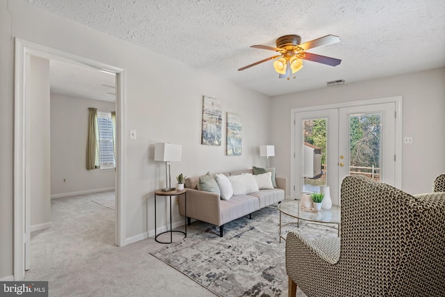 living room featuring ceiling fan, light colored carpet, a textured ceiling, and french doors