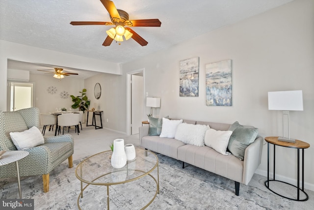 living room with ceiling fan, an AC wall unit, light colored carpet, and a textured ceiling