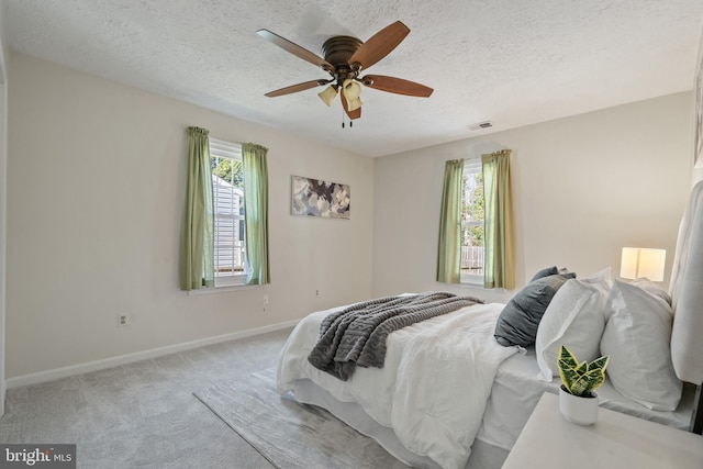 carpeted bedroom with ceiling fan and a textured ceiling