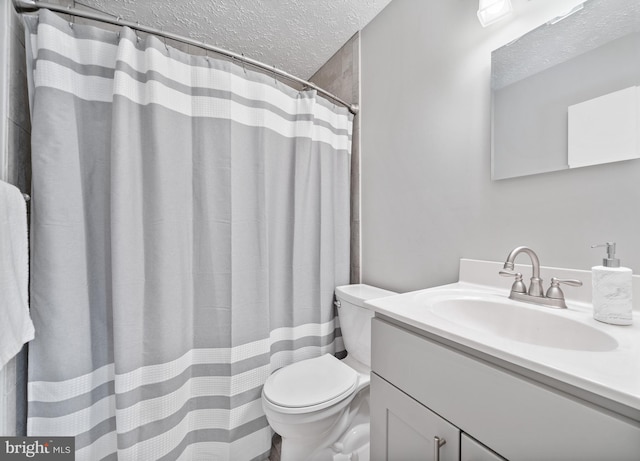 bathroom with vanity, toilet, and a textured ceiling