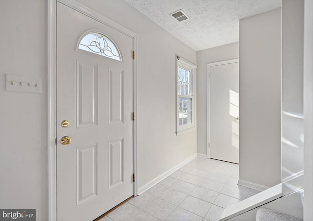 entrance foyer featuring light tile patterned floors and a textured ceiling