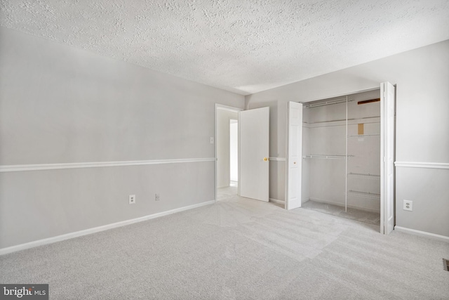 unfurnished bedroom featuring light colored carpet, a textured ceiling, and a closet