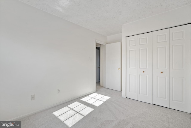 unfurnished bedroom with light colored carpet, a closet, and a textured ceiling