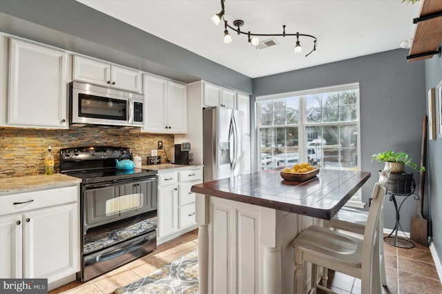 kitchen featuring a breakfast bar area, stainless steel appliances, tasteful backsplash, white cabinets, and a kitchen island