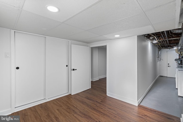 basement with dark hardwood / wood-style flooring and a paneled ceiling