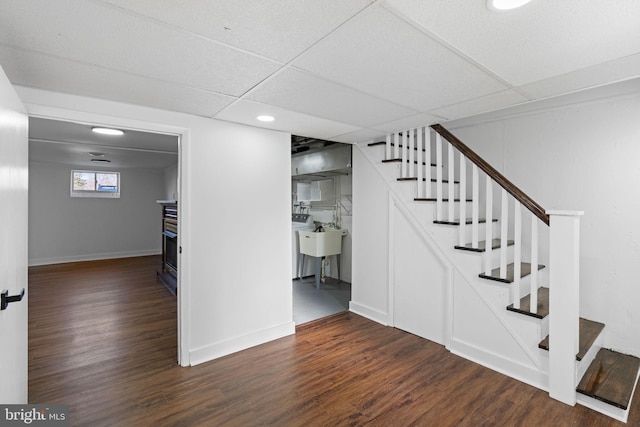 stairs with a paneled ceiling, wood-type flooring, and sink