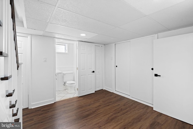 basement with dark hardwood / wood-style flooring and a drop ceiling