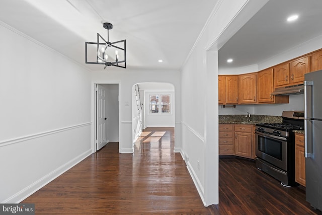 kitchen featuring appliances with stainless steel finishes, dark hardwood / wood-style floors, dark stone counters, hanging light fixtures, and ornamental molding