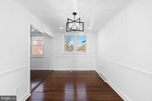 unfurnished dining area featuring a notable chandelier, crown molding, and dark wood-type flooring