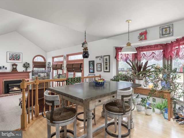 kitchen featuring light wood-type flooring, a brick fireplace, and vaulted ceiling