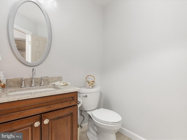 bathroom with toilet, baseboards, and vanity