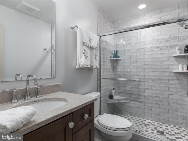 bathroom featuring vanity, a shower stall, and toilet