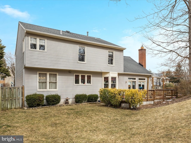 back of property featuring a deck, a yard, a chimney, and fence