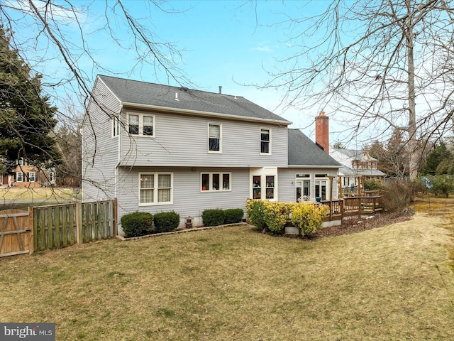 back of house featuring a deck, a lawn, a chimney, and fence