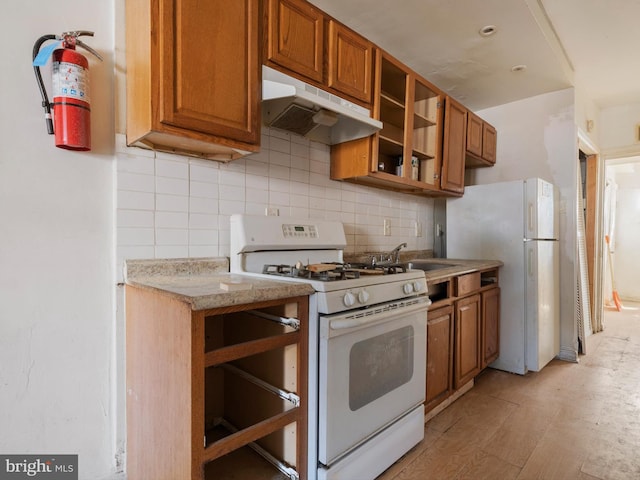 kitchen featuring light stone countertops, sink, backsplash, and white appliances