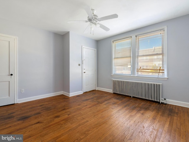 spare room with dark wood-type flooring, ceiling fan, and radiator heating unit