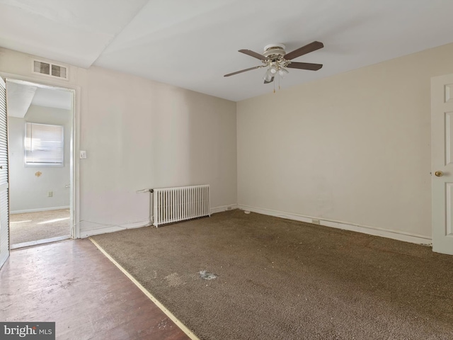 unfurnished room with ceiling fan and radiator