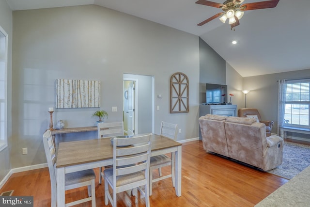 dining space with ceiling fan, wood-type flooring, and high vaulted ceiling