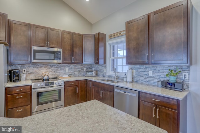 kitchen featuring lofted ceiling, sink, tasteful backsplash, appliances with stainless steel finishes, and light stone countertops