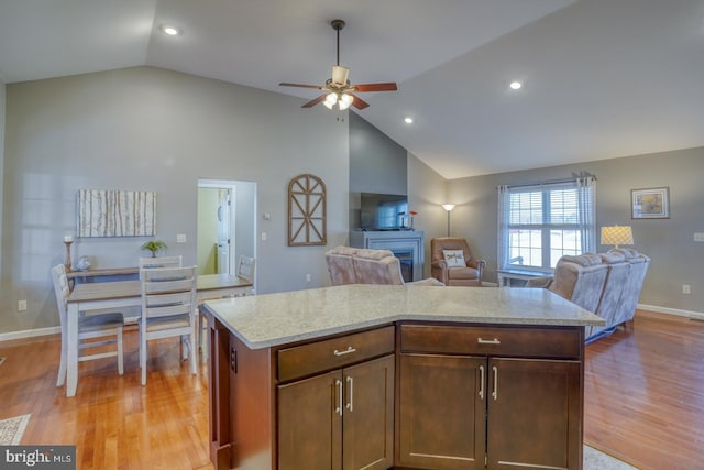 kitchen with ceiling fan, a center island, light hardwood / wood-style floors, and light stone countertops