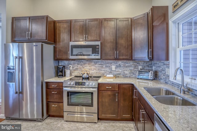 kitchen featuring tasteful backsplash, appliances with stainless steel finishes, sink, and light stone counters