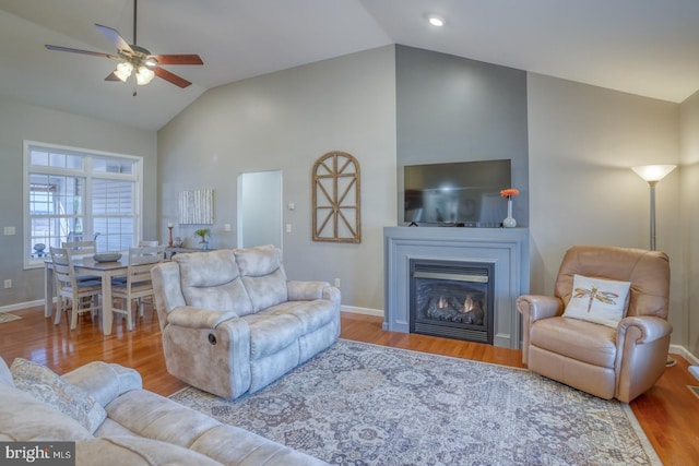 living room featuring ceiling fan, lofted ceiling, and light wood-type flooring