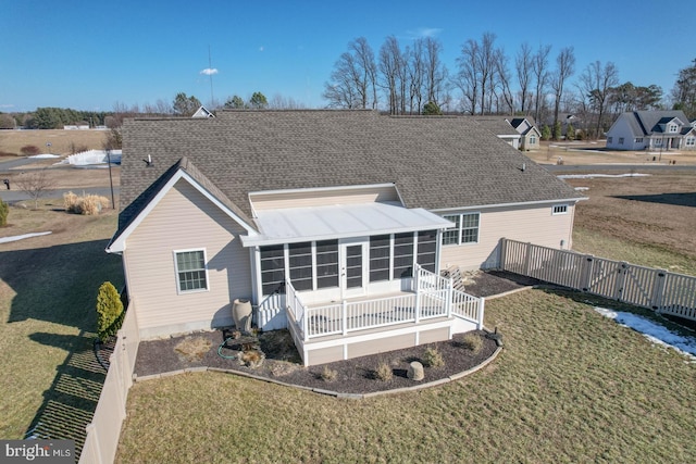 rear view of property featuring a sunroom and a lawn