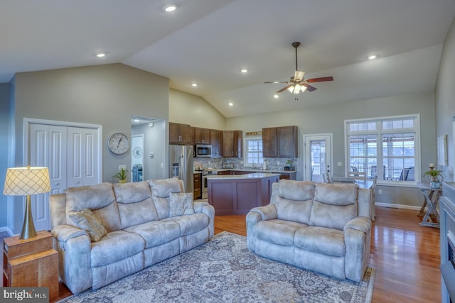 living room featuring lofted ceiling, ceiling fan, and light wood-type flooring