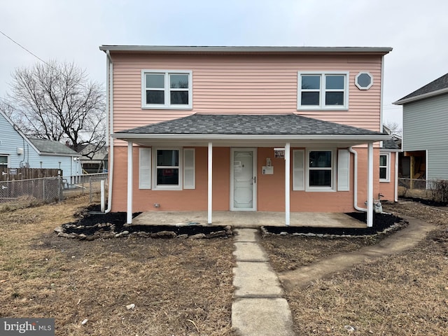 view of front of home with covered porch, a shingled roof, and fence