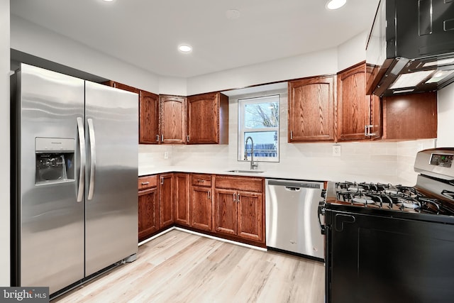 kitchen featuring a sink, light countertops, appliances with stainless steel finishes, backsplash, and light wood finished floors