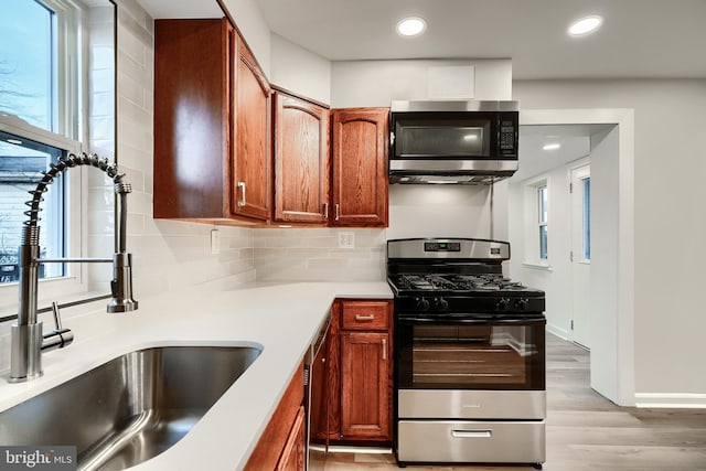 kitchen with recessed lighting, a sink, light wood-style floors, appliances with stainless steel finishes, and tasteful backsplash