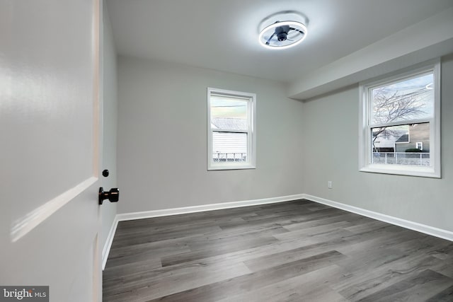 unfurnished room featuring baseboards and dark wood finished floors