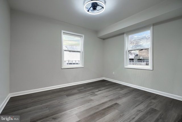 spare room featuring dark wood finished floors and baseboards