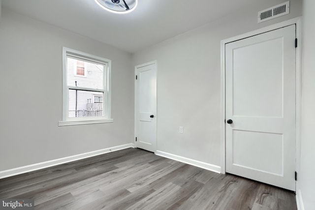 unfurnished bedroom with wood finished floors, visible vents, and baseboards