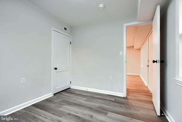 empty room featuring visible vents, baseboards, and wood finished floors