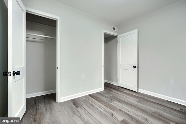 unfurnished bedroom featuring baseboards, visible vents, and wood finished floors