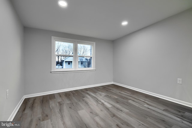 spare room with baseboards, wood finished floors, and recessed lighting