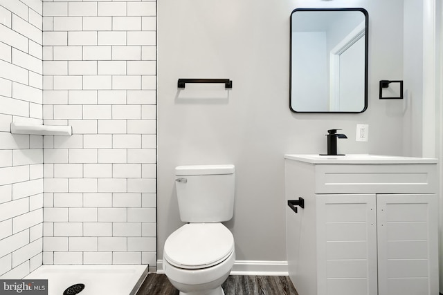 full bathroom with toilet, a tile shower, wood finished floors, and vanity