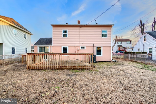 rear view of property with a fenced backyard, a chimney, and a wooden deck