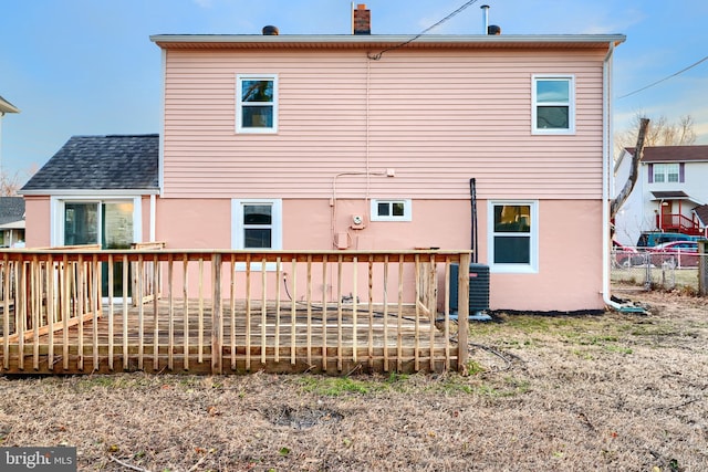 rear view of property with stucco siding, a chimney, cooling unit, and a wooden deck