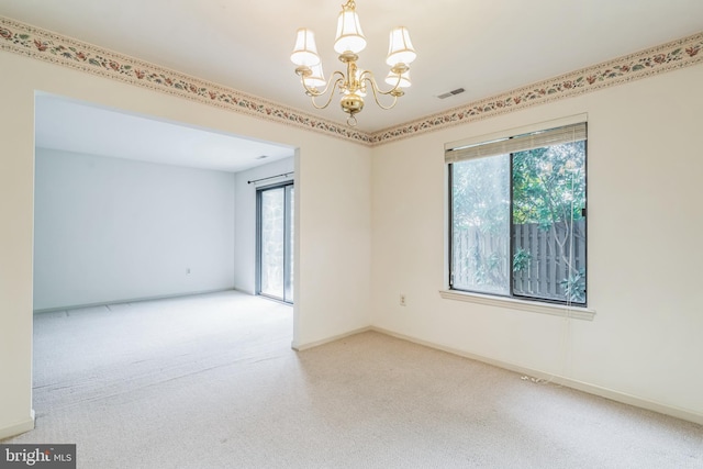 carpeted spare room with plenty of natural light and an inviting chandelier